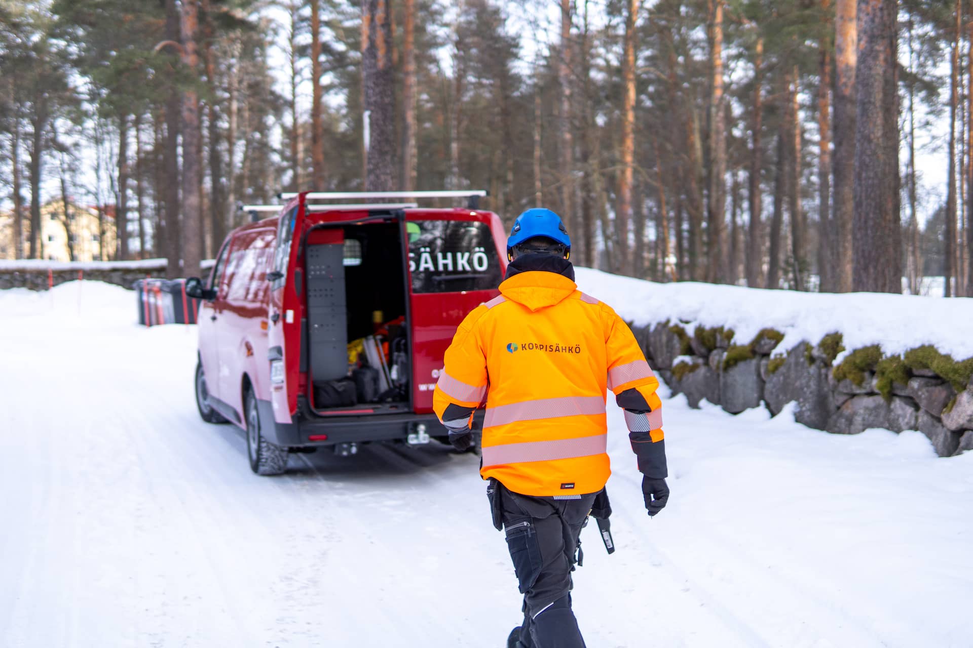 Korpisähkön asentaja huoltoauton luona talvisessa pihassa